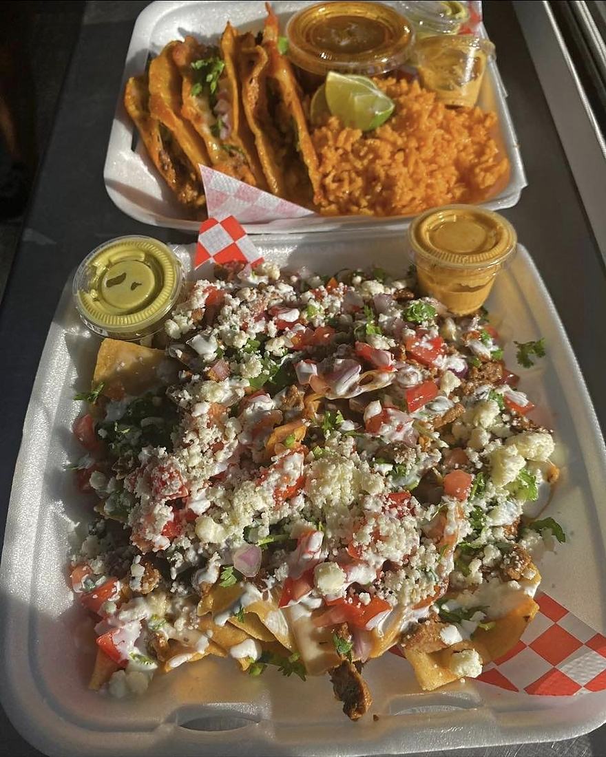 Photo from La TacoTrona's own Google listing: a tray of Mexican nachos under cheese, cream, cilantro and pico, beside a tray of tacos with rice.